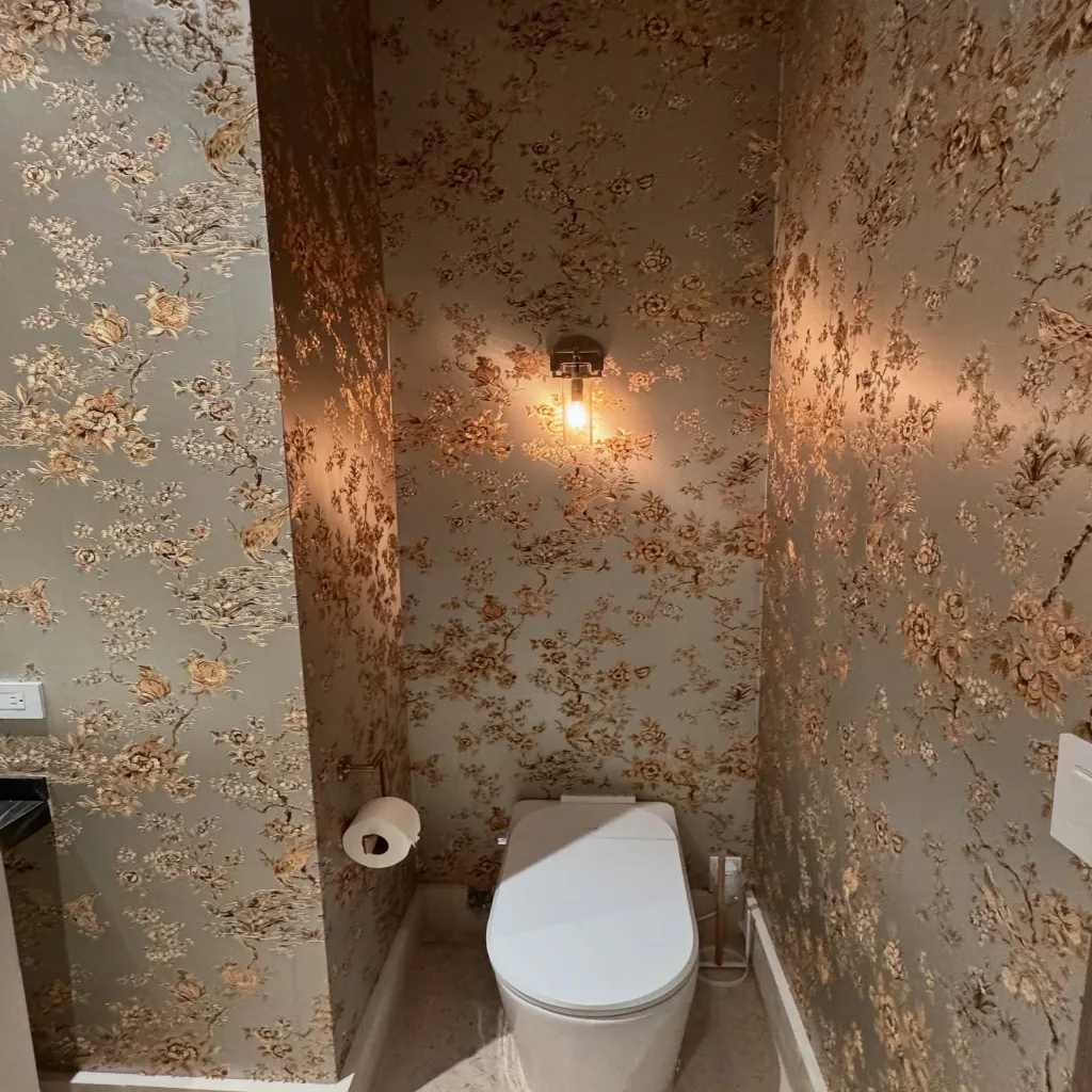 A homeowner seeing their finished room for the first time, hand to their mouth, delighted and entirely unposed