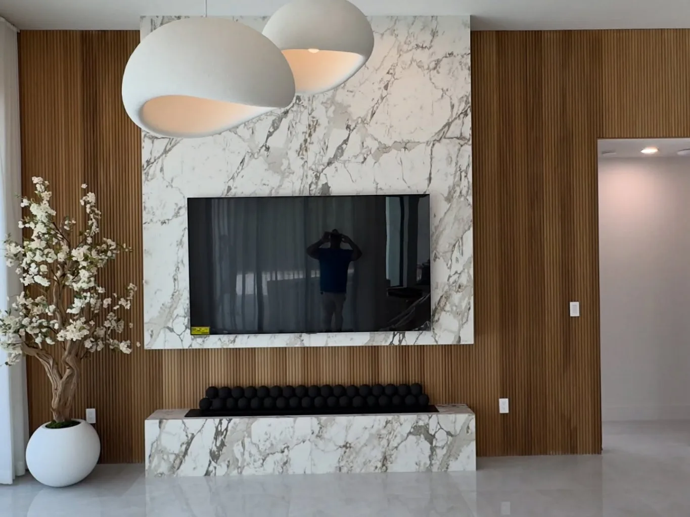 At the fitting stage, a wallpaper installer uses a broad pressure roller to secure acoustic wall covering across an upper wall, working from the center toward the edge
