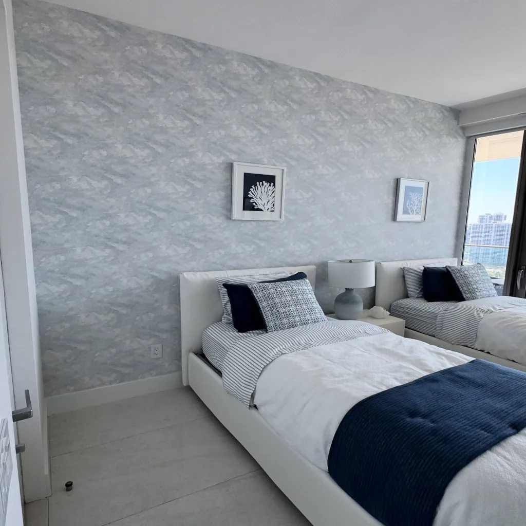 A set of tools — a smoothing brush and a seam roller — laid down on a clean surface beside the wallpaper work they have just finished, everything tidy and put away